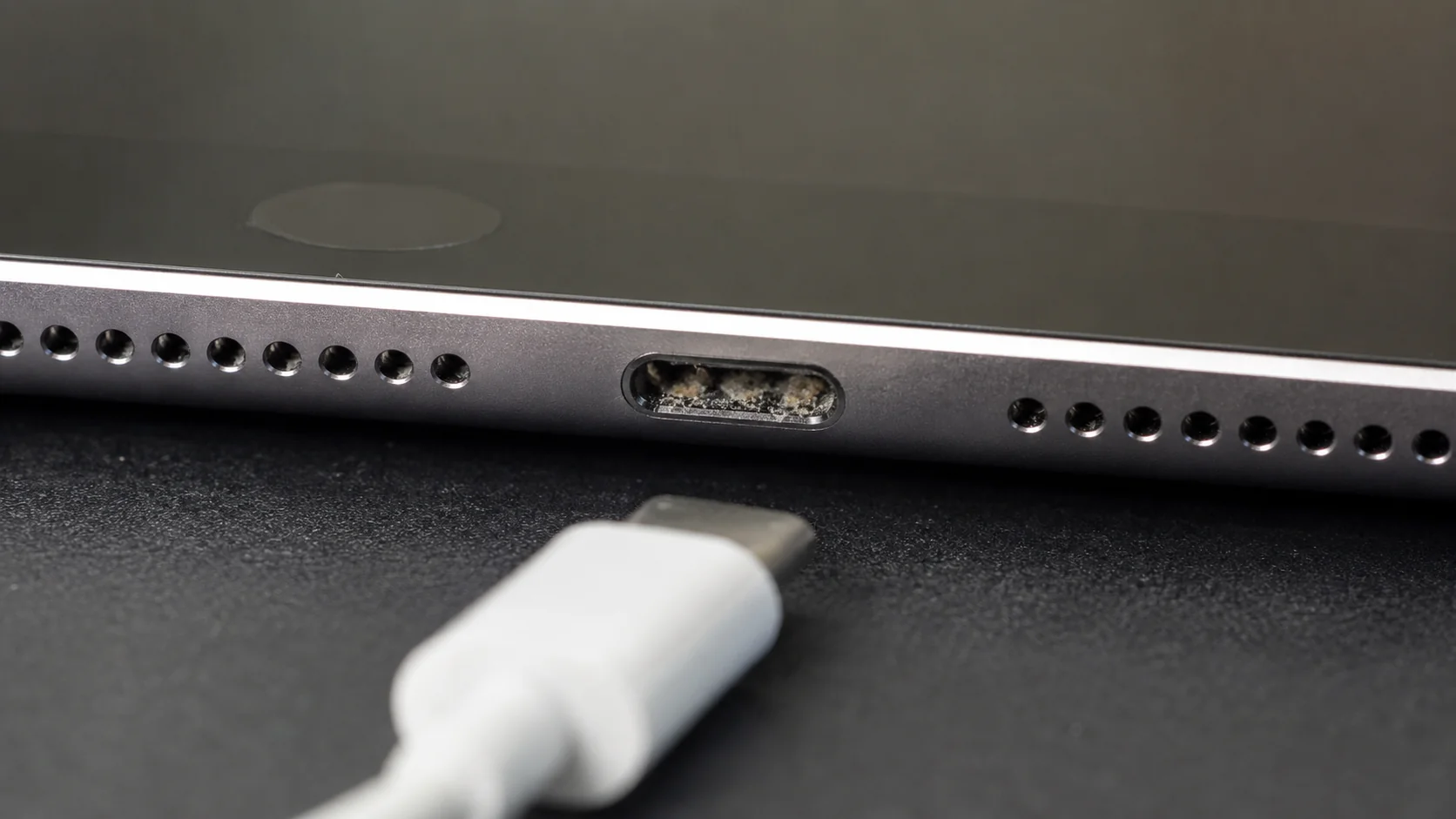 Debris inside an iPad USB-C charging port beside a charging cable
